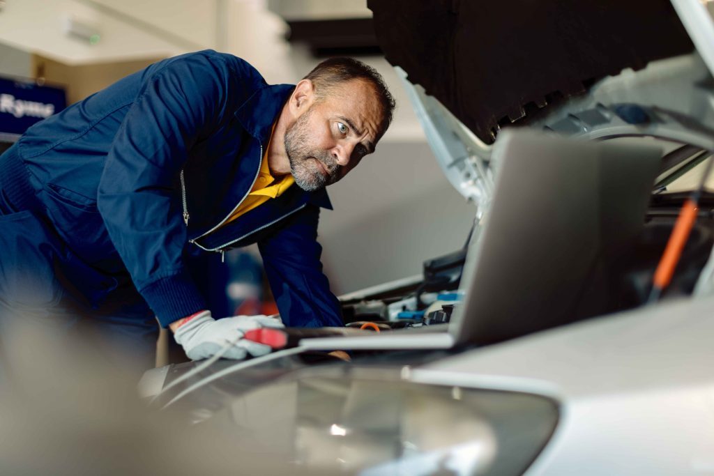 Mecanico realiza el mantenimiento por medio de una computadora a un vehiculo.